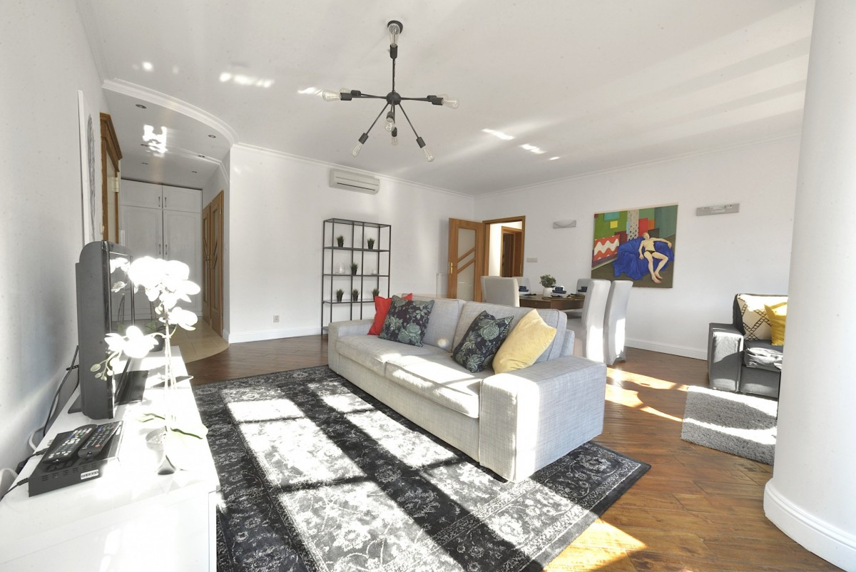 A sunlit dayroom with pictures on the walls and large sofas